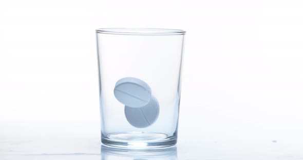 Tablets Falling into a Glassagainst White Background, Slow Motion 4K alt