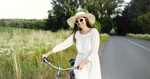 Woman Walking with Bicycle on Country Road