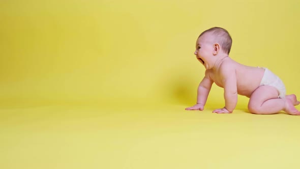 Happy toddler baby plays laughing on studio yellow background. Funny child boy