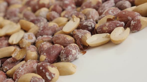 Tasty snack Arachis hypogaea slow pan 4K 2160p 30fps UltraHD footage - Roasted peanuts on white back alt