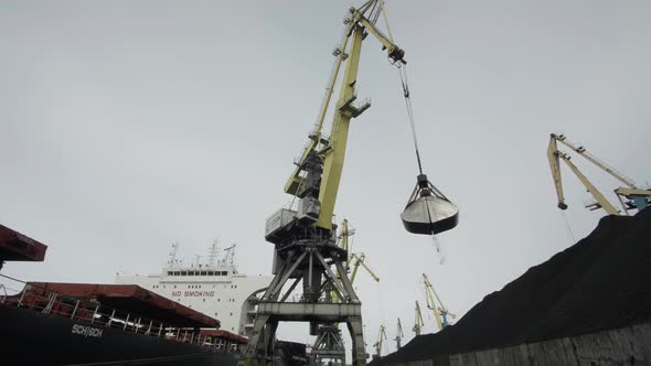 Coal is Poured From a Rail Crane Bucket Into the Tanks of a Huge Sea Coal Carrier Vessel