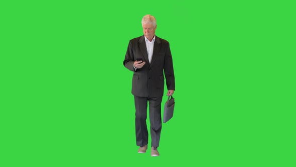 Old Businessman Walking and Texting on the Phone on a Green Screen, Chroma Key. alt