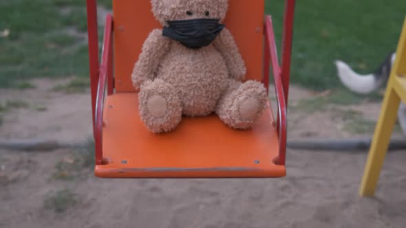 Teddy toy on a swing.  alt