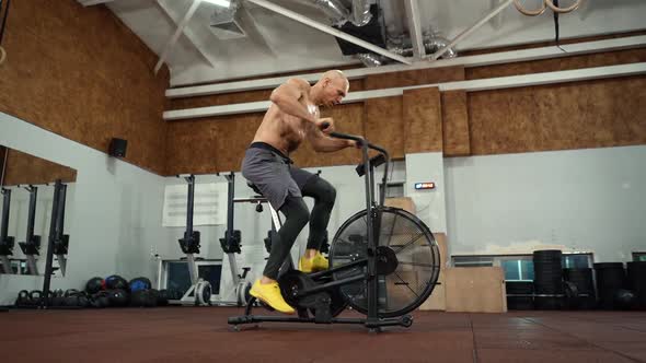 Strong athlete doing cardio workout on air bike alt