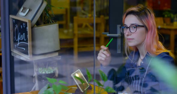 Female owner having cold coffee while writing on a notepad alt