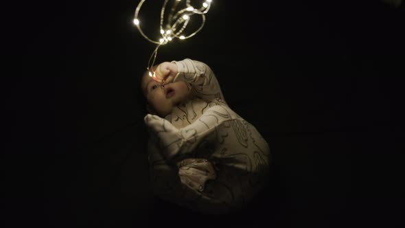 A Child Plays in the Dark with a Christmas Glowing Garland. Merry Christmas Christmas and Happy New alt