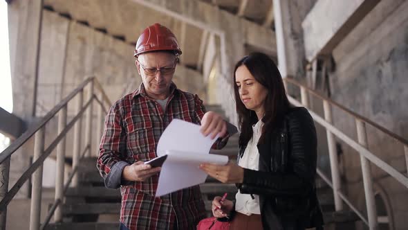 Female Engineer Inspects the Construction and Communicates with the Foreman alt