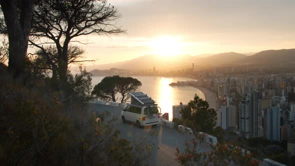 Camping RV Van Caravan Parked at Sunset Over City alt