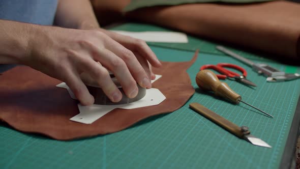 Worker Using Awl Marking Outline of Leather Detail on Scale Mat Indoor alt