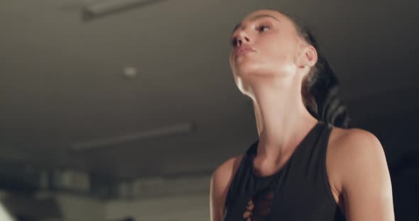 Athletic Girl with Hair Tied in a Ponytail Stepping on a Treadmill in a Gym alt