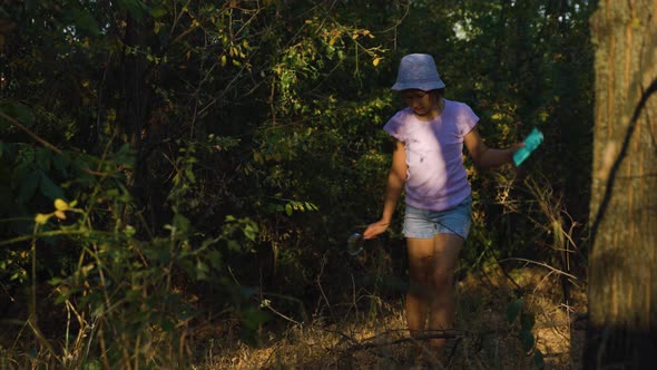 Tracking Shot of the Child Girl in Search of Adventure in the Forest Discovers the Surrounding World alt