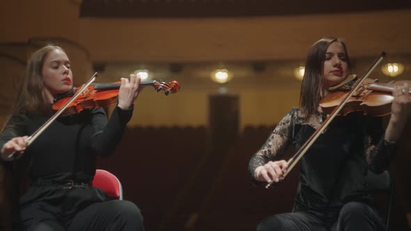 Female Violinists are Playing Music in Orchestra Sitting on Scene of Philharmonic Hall alt