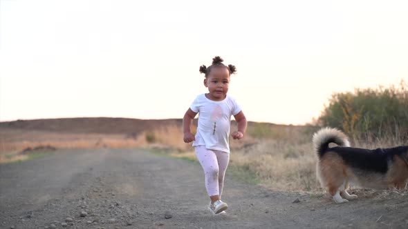 Small South African girl running with a dog on a grey gravel road in a country winter landscape at d alt