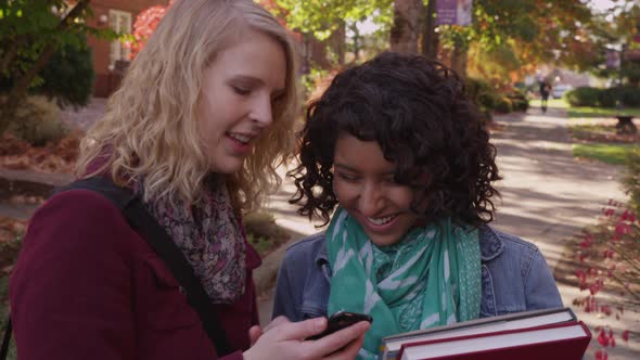 Two college students on campus looking at cell phone