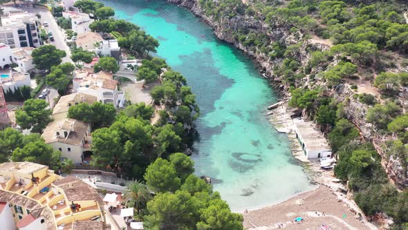 Cala Pi Beach in Mallorca Spain with swimmers and cliff beach homes, Aerial pan left shot alt