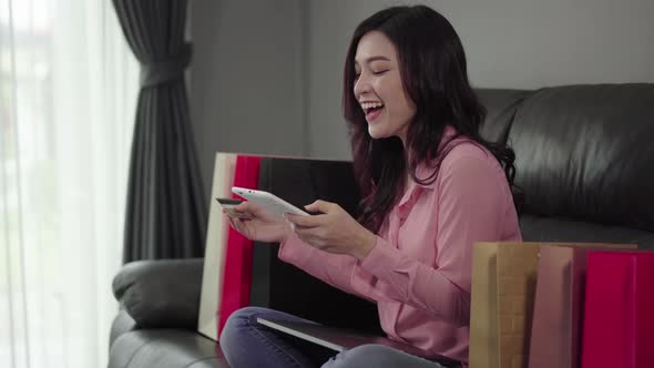 happy woman using digital tablet for online shopping with credit card in the living room