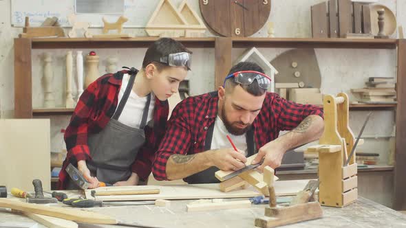 Male Teacher and His Male Pupil Making By Hand a DIY Wooden Toy
