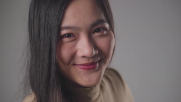 Confident asian woman happy standing smilling and looking at camera standing over background.