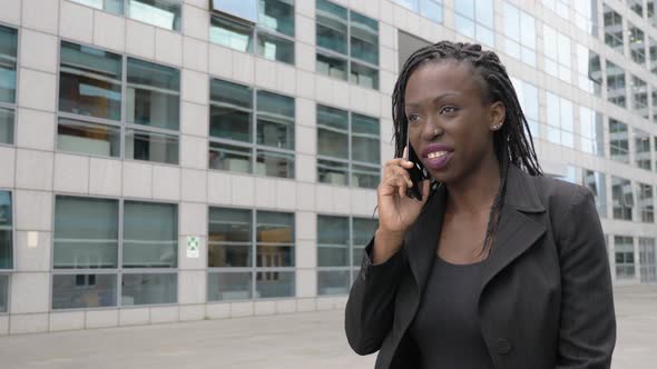 smiling succesful young black african businesswoman talking by phone in the city alt