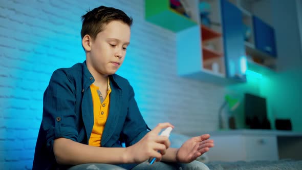 boy use disinfectant spray to protect his hand due to coronavirus epidemic. alt
