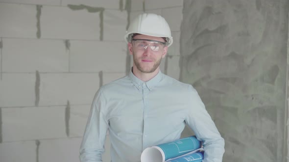 Young engineer-architect with  blueprints looks at the camera  alt