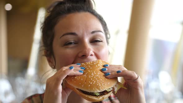 Young Pretty Woman Eating a Hamburger