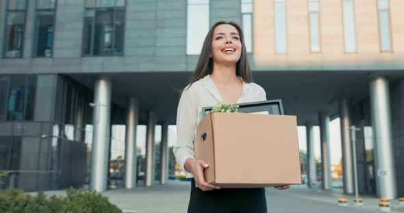 Atractive Beautiful Smiling Brunette in a Shirt Stands in Front of a Glass Modern Company Building alt