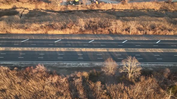 An aerial view of a salt marsh next to a multilane road with a few cars driving by, shot on a sunny alt