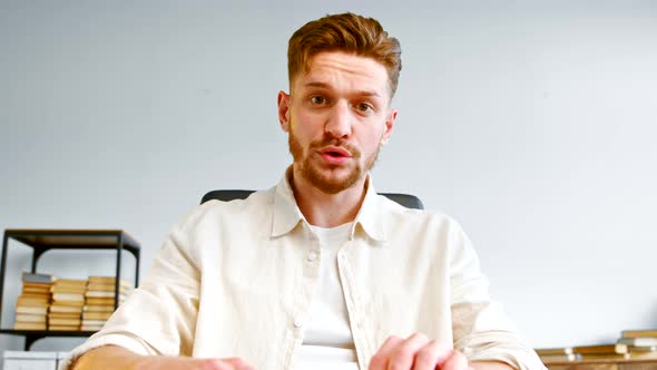 Angry bearded company manager in yellow shirt talks at online meeting alt