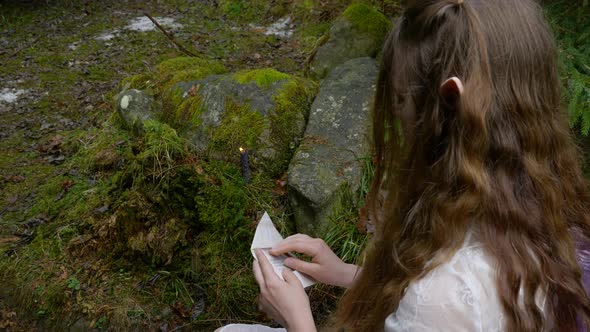 An Elf Girl in a White Dress Opens an Envelope with Letters in the Forest alt