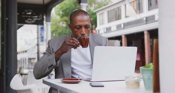 African American man drinking a coffee and using a laptop alt