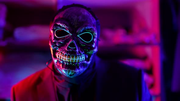 Gloomy Man with Face Mask of Scaring Skull in Nightclub in Halloween Night alt