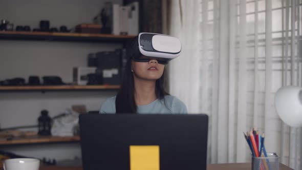 Happy Asian girl using 3D virtual reality headset at home.