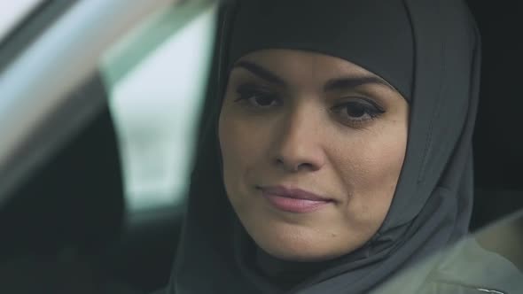 Muslim Woman Rolling Car Window Down to Check Road, Attentive Driver, Closeup alt