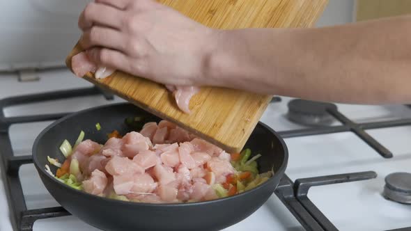 Add meat to vegetables. A pan with vegetables is on the gas stove. alt