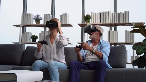 Senior couple playing a video game with joysticks and having fun with virtual reality glasses