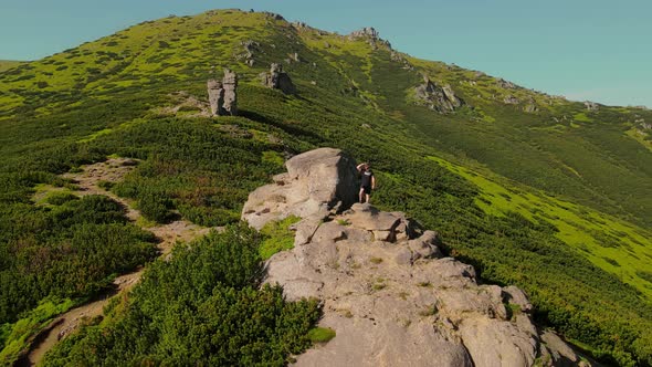 Hiker Stands on a Rock Looking to the Future at Sunset alt