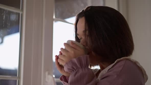 Closeup Happy Little Woman Drinking Coffee in Sunshine in the Morning Standing at Home Indoors alt