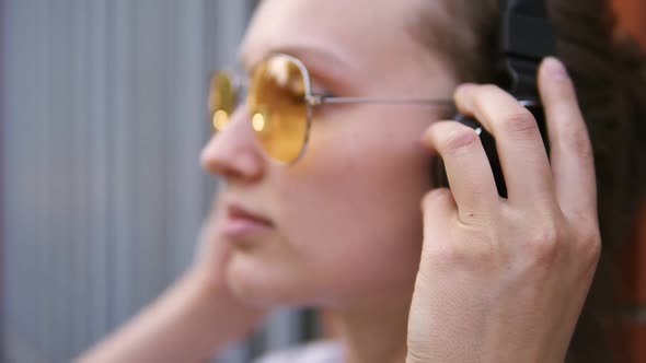 Young Caucasian Woman with Black Headphones Outdoors on Sunny Summer Day alt