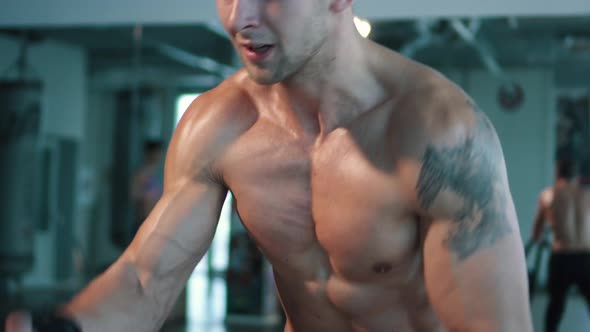 Tilt Up To Closeup of Man's Face Working Out with Battle Ropes alt