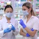 Young Professional Asian and Caucasian Women Discussing Efficiency of Drugs with Blurred Client - VideoHive Item for Sale