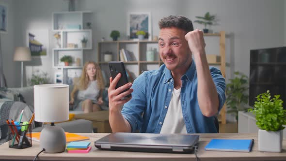 Couple Winners Hold Smartphone Feel Amazed Overjoyed with Mobile Online Bet Bid App Game Win alt