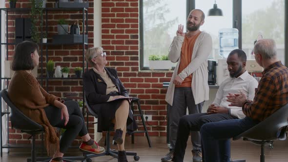 Happy Man Sharing Therapy Progress with Group of People at Aa Meeting Celebrating Together alt