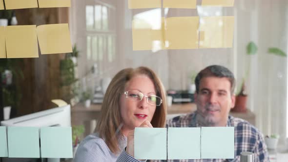 Team of Successful People Sharing Great Ideas on Their Sticky Notes on a Glass Door alt
