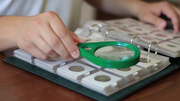 Man Examining Collection Of Coins In Album