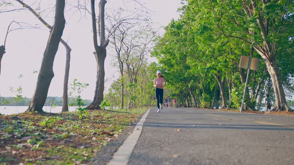 Asian young beautiful sport woman running on street in public park. alt