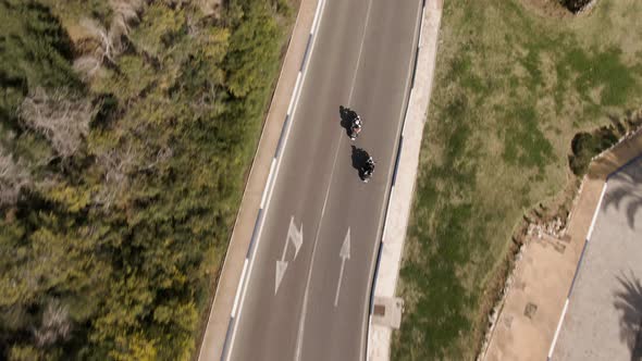 High angled drone shot following tourists riding motorbikes in Spain alt