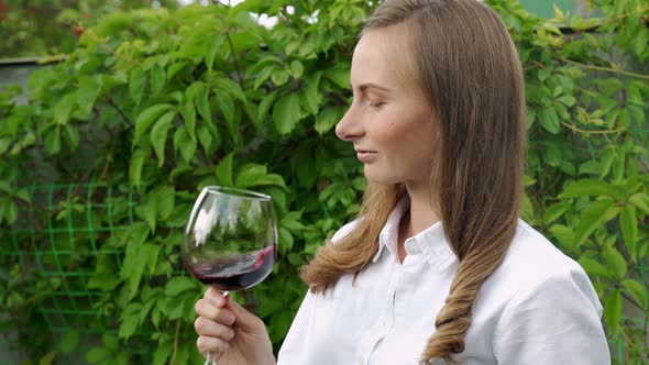 Young Woman Drinks Red Wine in a Vineyard on a Sunny Day alt