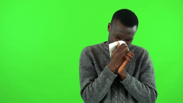 A Young Black Man Blows His Nose Into a Paper Tissue - Green Screen Studio alt