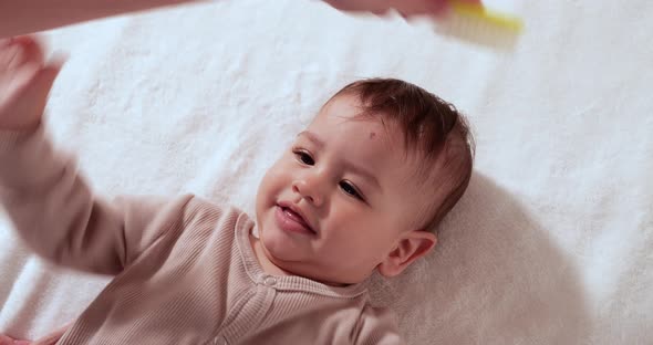 Mother Combing Tiny Hairs on Her Newborn Baby's Head As She Wakes Up alt